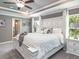 Spacious primary bedroom featuring a decorative white headboard, tray ceiling, and natural light from the windows at 1001 Aruba Ave, Mulberry, FL 33860