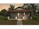 Charming home featuring a cozy front porch with decorative railing, a walkway, and mature trees at 1243 Olive St, Lakeland, FL 33815