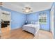 Bedroom with a ceiling fan, light blue walls, wood-look floors, and view to living room at 1415 Pinewood Ave, Lakeland, FL 33803