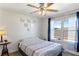 Bright bedroom features a ceiling fan, wall decor, and a window with blue patterned curtains at 14439 Prunningwood Pl, Winter Garden, FL 34787