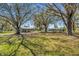 Large backyard with mature trees offering shade and a view of detached garage at 2465 Thornhill Rd, Auburndale, FL 33823