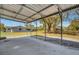 Covered carport with concrete floor overlooks spacious backyard with mature trees offering ample space at 2465 Thornhill Rd, Auburndale, FL 33823