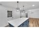 Open kitchen boasts a blue island, quartz counters, modern pendant lighting and white shaker cabinets at 2465 Thornhill Rd, Auburndale, FL 33823