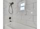 Newly renovated shower with tub featuring white marble-patterned tile and dark fixtures at 2465 Thornhill Rd, Auburndale, FL 33823