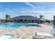 Community pool with covered lounge area, lounge chairs, palm trees and clear blue sky at 4525 Breccia Ln, Lakeland, FL 33811