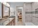 Renovated bathroom with marble countertops, a wood cabinet vanity, and a tiled shower at 4769 Highlands Place Cir, Lakeland, FL 33813