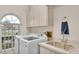 Bright laundry room features modern washer, dryer, storage cabinets, sink, and window at 4769 Highlands Place Cir, Lakeland, FL 33813