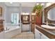 Bright main bathroom showcases vanity, soaking tub, glass block window, plants, and decorative mirror at 5118 Eagles Nest Dr, Lakeland, FL 33810