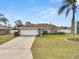 Charming single-story home with well-manicured lawn, mature palm trees, and a two-car garage under a bright blue sky at 5252 Montserrat Dr, Lakeland, FL 33812