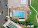 Aerial view of a community pool with lounge chairs, shaded seating, adjacent parking, shuffleboard, and a green space at 5725 Mallard Dr, Lakeland, FL 33809