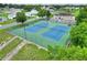 Aerial view of tennis courts with green and blue surfacing, green fencing, mature trees and landscaping, and parking at 5725 Mallard Dr, Lakeland, FL 33809