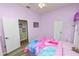 A purple bedroom with wood look floors, a decorated wall, and two doors leading to other rooms at 7211 Scenic Hills Blvd, Lakeland, FL 33810