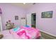 Bright bedroom features a pink and blue comforter, wood look flooring, and a view into the en-suite bathroom at 7211 Scenic Hills Blvd, Lakeland, FL 33810