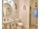Cozy bathroom with pedestal sink, toilet, beach-themed decor and access to the shower at 1 Lake Eloise Ln, Winter Haven, FL 33884