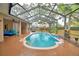 Enclosed pool featuring a waterfall, spacious deck, and screened enclosure for year-round enjoyment at 1 Lake Eloise Ln, Winter Haven, FL 33884