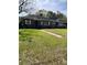 Single-story home boasts lush green front yard, a walkway, and mature trees at 1197 De La Palma Ave, Bartow, FL 33830