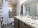 Bathroom with double sink vanity, tile surround tub/shower, window, and gray plank flooring at 1758 Burrows Ave, Lakeland, FL 33811