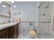 Well-lit bathroom with a glass shower enclosure, white tile, dark wood vanity, and a decorative mirror at 2020 Indian Trl, Lakeland, FL 33813
