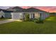 Charming single-story home with well-manicured lawn and two car garage, set against a colorful sky at 236 Talladega Ln, Polk City, FL 33868