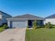 Charming single-story home with a gray exterior, well-manicured lawn, and attached two-car garage at 236 Talladega Ln, Polk City, FL 33868