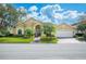 Charming tan single-story home featuring a lush green lawn, mature landscaping, and a welcoming front entrance at 2900 Grasslands Dr, Lakeland, FL 33803