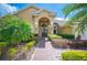 Close-up of a tan home featuring a brick walkway, mature landscaping, and a charming double-door entrance at 2900 Grasslands Dr, Lakeland, FL 33803