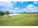 Picturesque golf course with lush green grass and a pond under a bright, cloudy sky at 2900 Grasslands Dr, Lakeland, FL 33803