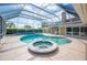 Beautiful screened-in pool with attached hot tub and a travertine patio at 2900 Grasslands Dr, Lakeland, FL 33803