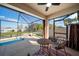 Enclosed patio has an exterior view overlooking the pool with comfortable furniture and a ceiling fan at 474 Cedar Glen Dr, Lake Alfred, FL 33850