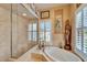 Main bathroom with a glass shower, a soaking tub, and a plantation shuttered window at 565 Osprey Landing Dr, Lakeland, FL 33813