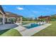 Backyard showcases a pool with a tanning ledge, spa, outdoor living room, outdoor kitchen, pergola and adjacent sport court at 5676 Case Ln, Lakeland, FL 33813
