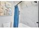 Bathroom featuring marble-look tile walls, blue shower curtain, and art at 6421 Highlands Oak Trl, Lakeland, FL 33813