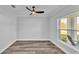 Bright, minimalist bedroom with wood flooring, a modern ceiling fan, and a large window at 6421 Highlands Oak Trl, Lakeland, FL 33813
