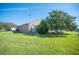 Expansive side yard with lush lawn, mature landscaping, and neutral-toned home exterior under a blue sky at 701 Reflections Dr, Winter Haven, FL 33884