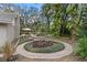 Landscaped backyard featuring a brick pathway that winds around a circular garden and leads to an outdoor dining area at 7010 Parliament Pl, Lakeland, FL 33809