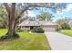 Beautifully landscaped home with mature trees, a circular garden, and a spacious driveway leading to an attached garage at 7010 Parliament Pl, Lakeland, FL 33809
