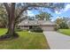 Charming single-Gathering home showcasing lush landscaping, mature trees, a manicured lawn, and an attached two-car garage at 7010 Parliament Pl, Lakeland, FL 33809