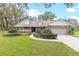 Well-maintained home with a lush lawn, decorative shrubbery, and a cozy front porch under a gray roof and dormer windows at 7010 Parliament Pl, Lakeland, FL 33809
