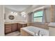 This bathroom features dual sinks, a soaking tub, and a window with natural light at 8158 Woodvine Cir, Lakeland, FL 33810
