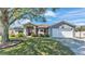 Beautiful home exterior featuring a well-maintained lawn, mature trees, and a two-car garage at 8158 Woodvine Cir, Lakeland, FL 33810
