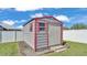 Exterior view of a gray and red storage shed in the backyard on a grassy lawn at 8158 Woodvine Cir, Lakeland, FL 33810