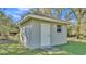 Close up of a gray shed with a white door and trim on a grassy lot at 9216 Tom Moore Rd, Lakeland, FL 33810