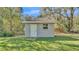 Small shed with a white door and window sits on a well-maintained lawn at 9216 Tom Moore Rd, Lakeland, FL 33810