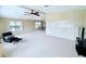 Bright living room with neutral carpet, wood-look paneled walls, ceiling fan and ample natural light at 1007 Elizabeth Ln, Lakeland, FL 33809