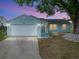 Charming light blue single-story home with a well-maintained lawn and two-car garage at dusk at 1064 Penguin Pl, Lakeland, FL 33809