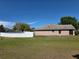 A view of the exterior of the home with a white fence and grass yard at 107 Amber Blvd, Auburndale, FL 33823