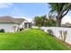 Spacious backyard featuring lush green grass, mature trees, and a white vinyl fence at 117 Belmont Dr, Winter Haven, FL 33884