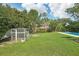 Lush backyard featuring a large grassy area, chicken coop, and pool at 1722 High Point Dr, Lakeland, FL 33813