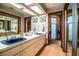 Traditional-style bathroom with double sinks, floral wallpaper, and access to the shower at 1842 Pinnacle Dr, Lakeland, FL 33813