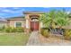 Charming home featuring a red double door entry, lush landscaping, stone accents and a decorative bench at 2030 Country Manor St, Bartow, FL 33830